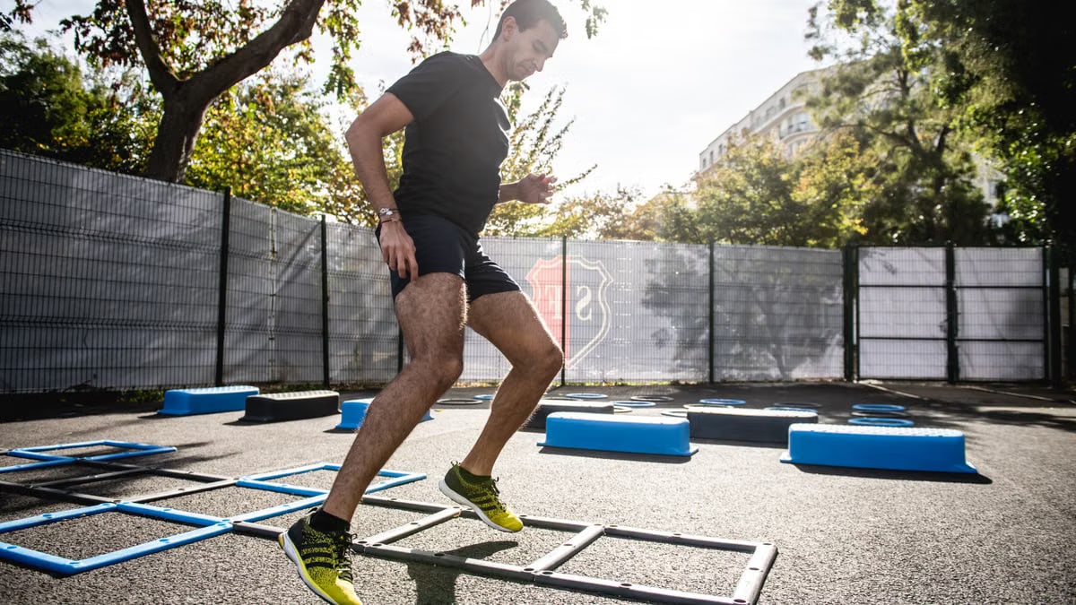 A man performing agility drills outdoors in a sunny park setting.